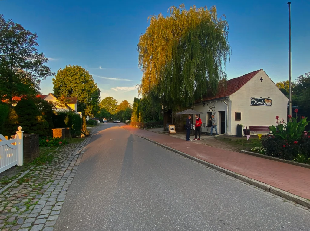 Straßenansicht mit Kieck In und Kunden bei schönem Wetter.